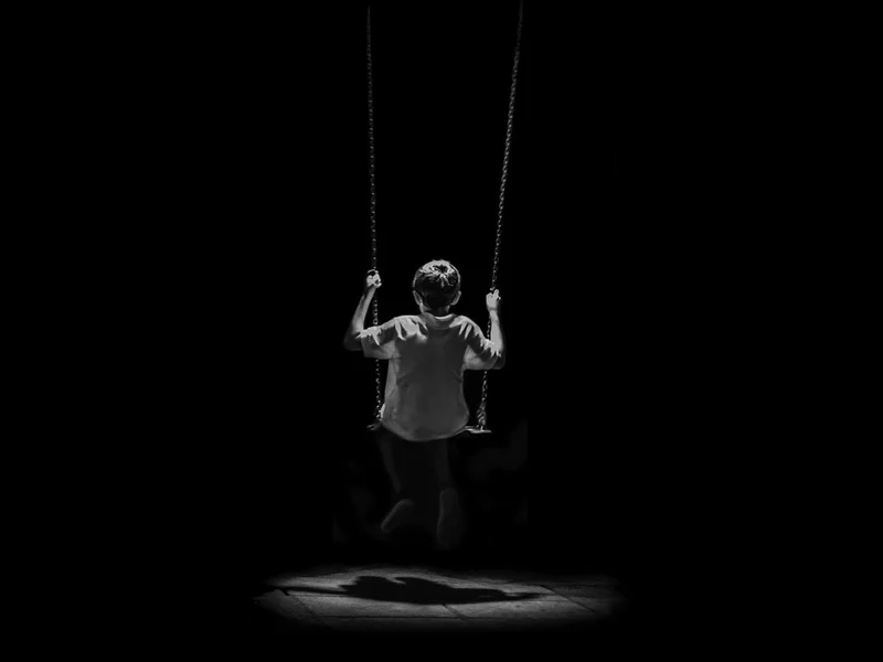 Child Swinging in Shadows