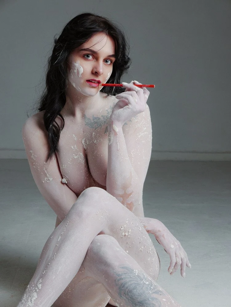 Brunette in white clay on a gray background