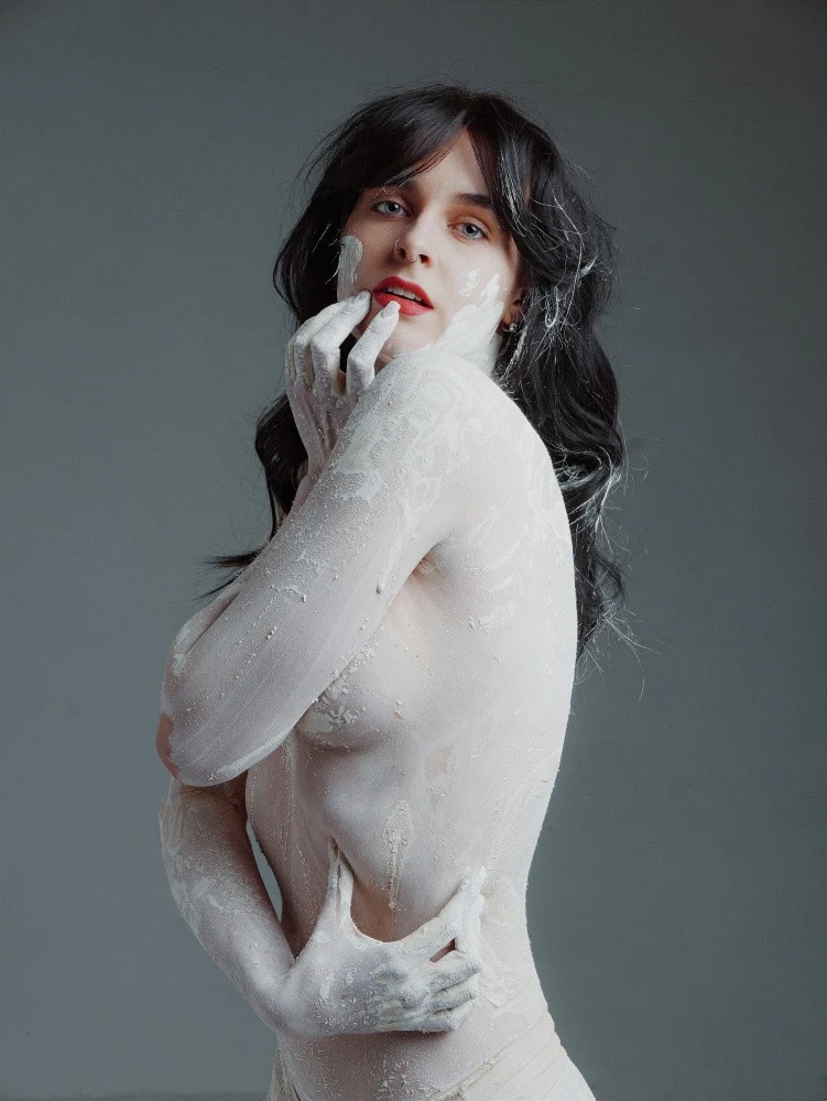 Brunette in white clay on a gray background